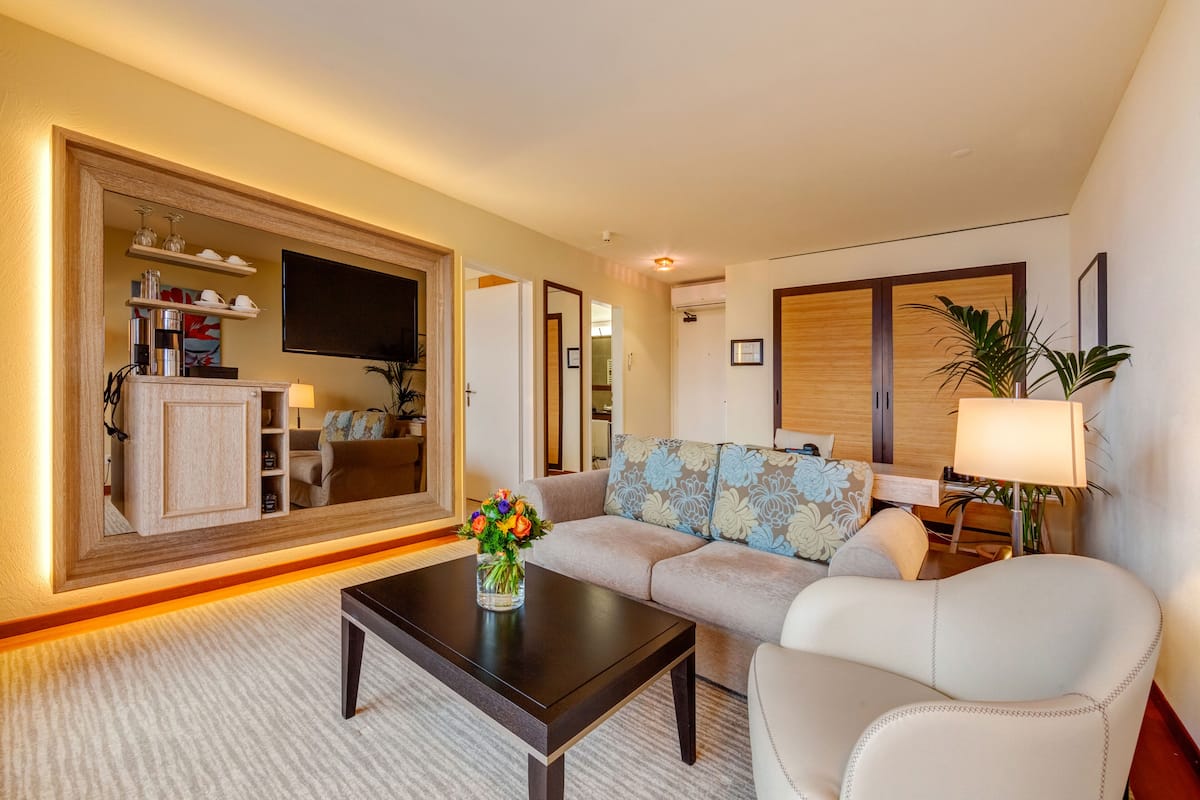 Una sala de estar moderna con un sofá, una mesa de centro, un televisor y un mueble aparador con estantes.