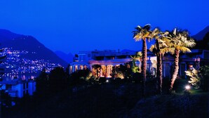 Un hotel moderno con una imponente vista de la montaña, senderos bien iluminados y exuberantes palmeras.