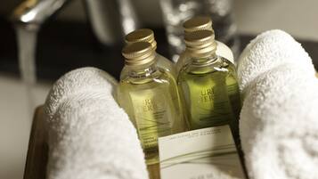 A wooden tray with two bottles of Pure Herbs shampoo and a white towel.