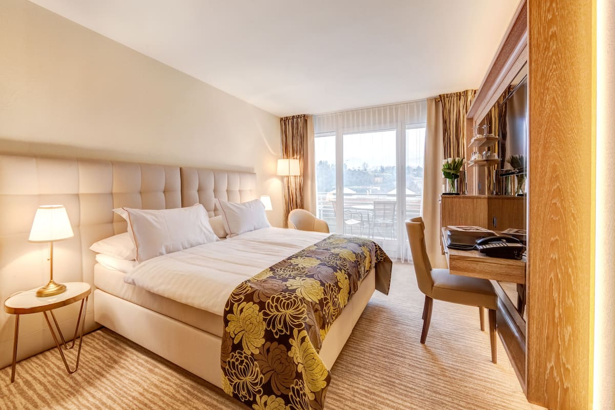 Habitación de hotel con una cama grande, un escritorio y vistas de la ciudad.