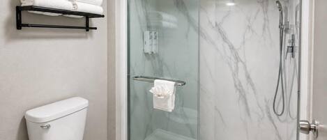A modern bathroom with a glass-enclosed shower, a toilet, and a towel rack with folded towels.