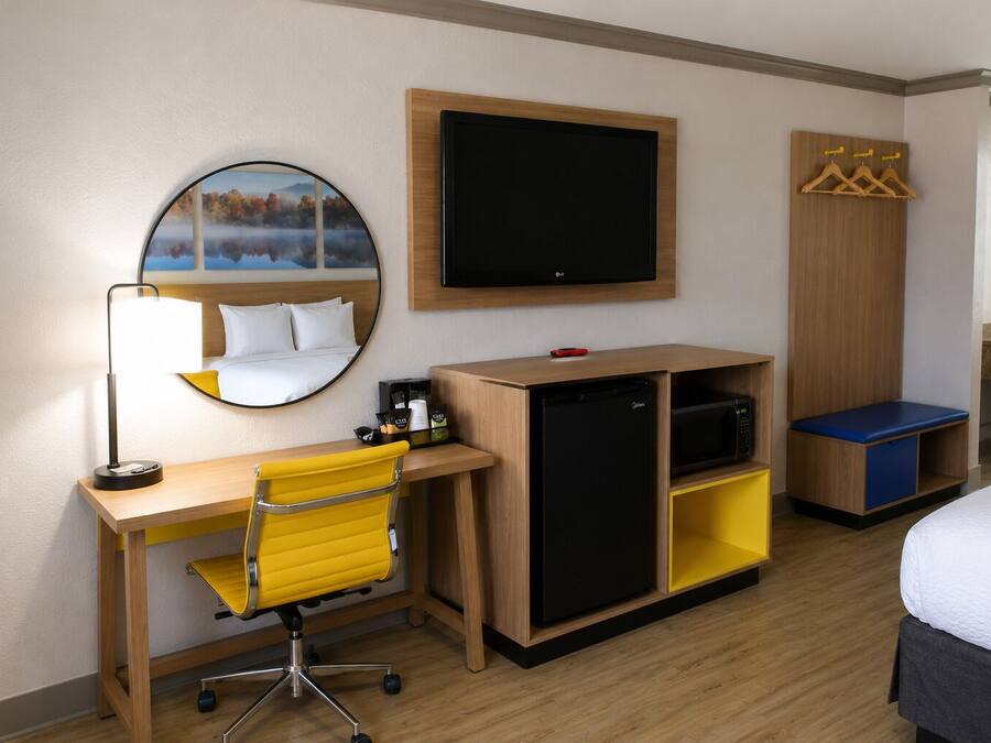 Habitación de hotel con cama, escritorio con silla, televisor, minibar y armario.