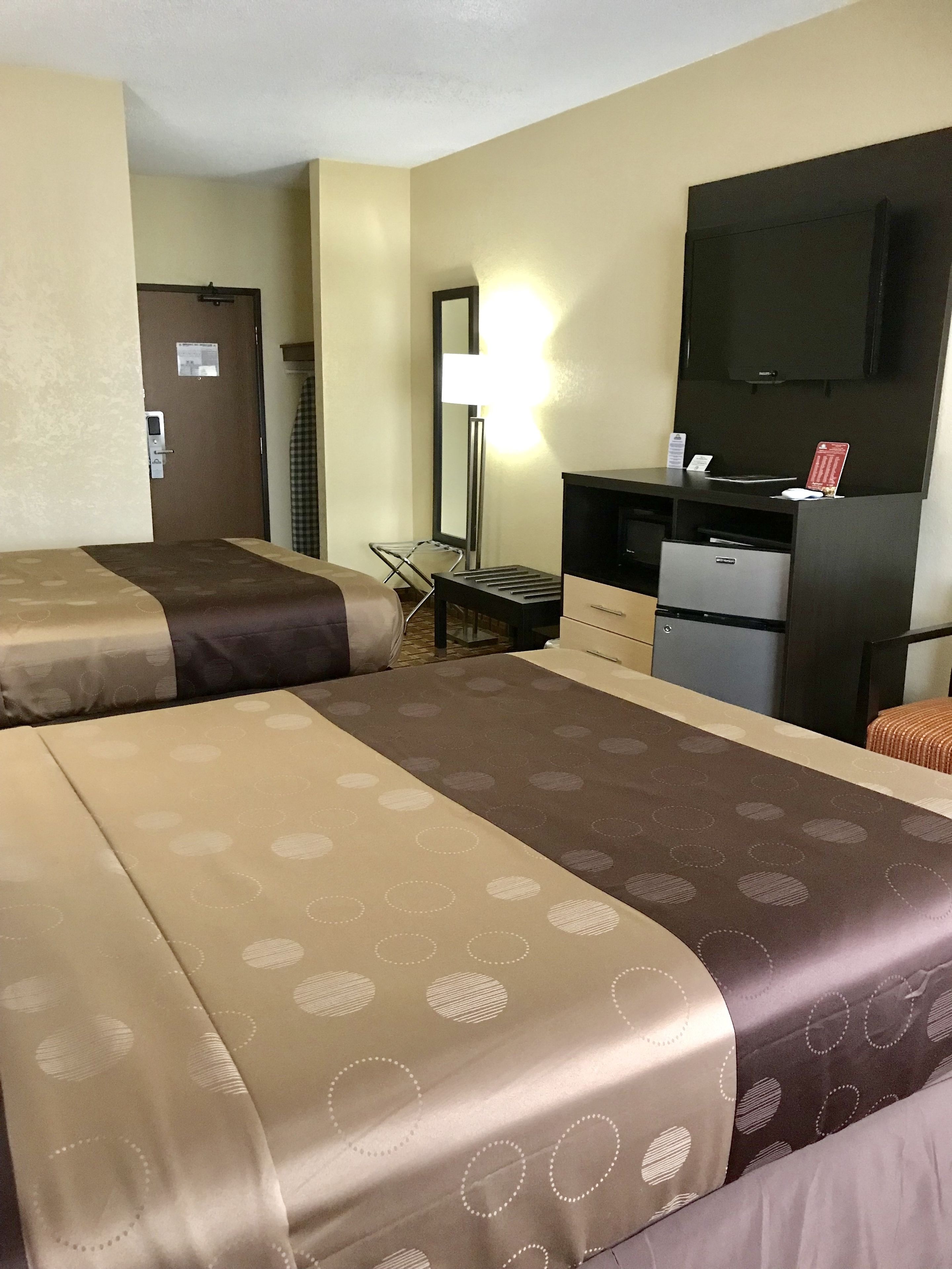Une chambre d’hôtel avec deux lits, un bureau avec un ordinateur, une télévision et une chaise.