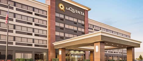 A modern hotel with a prominent 'La Quinta' sign, a covered entrance, and a parking lot.