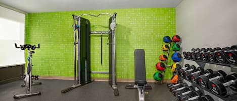 A gym with exercise equipment, a squat rack, and a rack of dumbbells.
