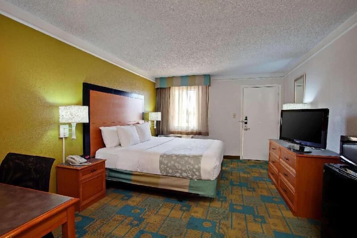 A hotel room with a bed, a television, a desk, and a chair.