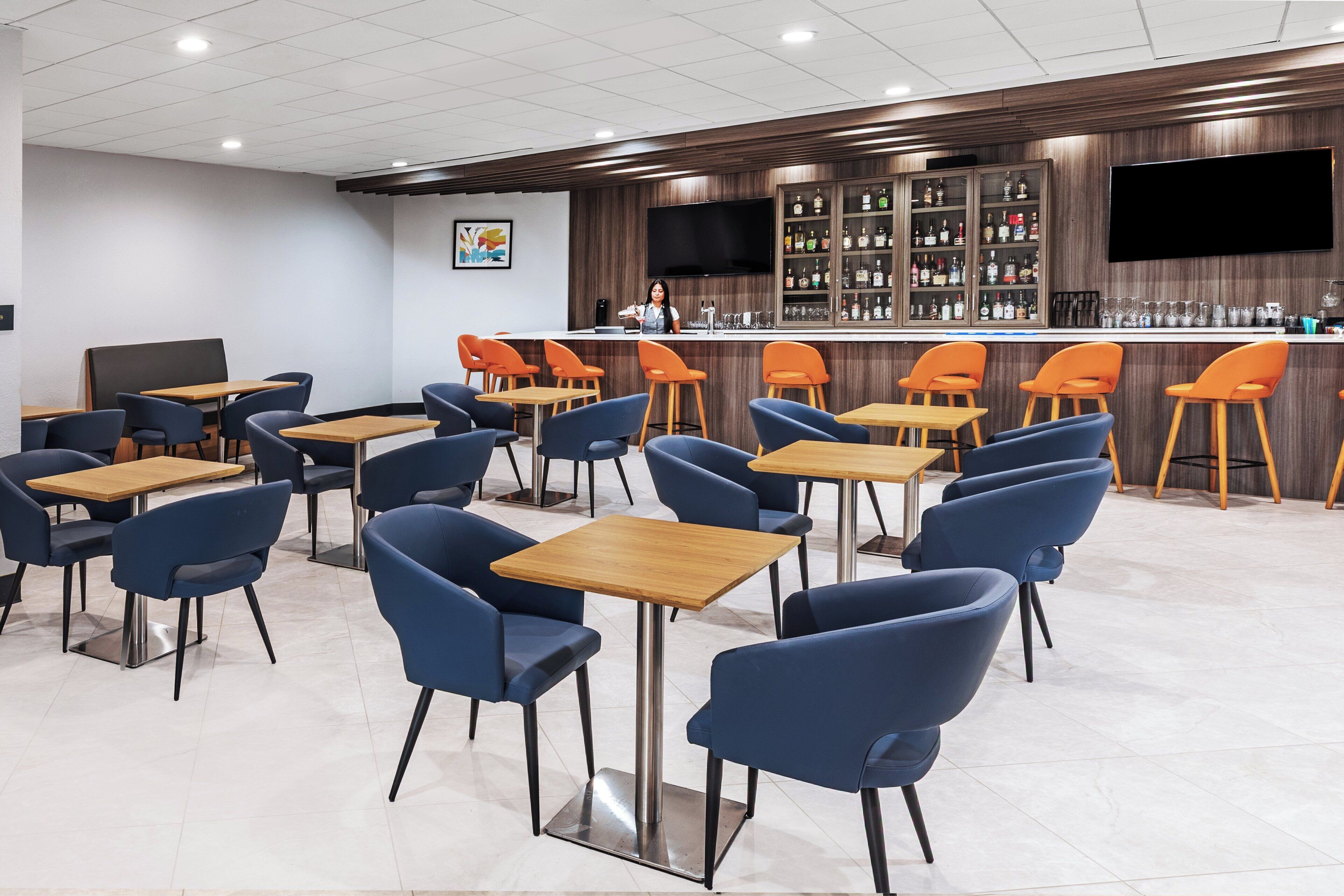 A modern bar area with a counter, bar stools, and a television screen.