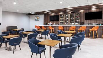 A modern bar area with a counter, bar stools, and a television screen.