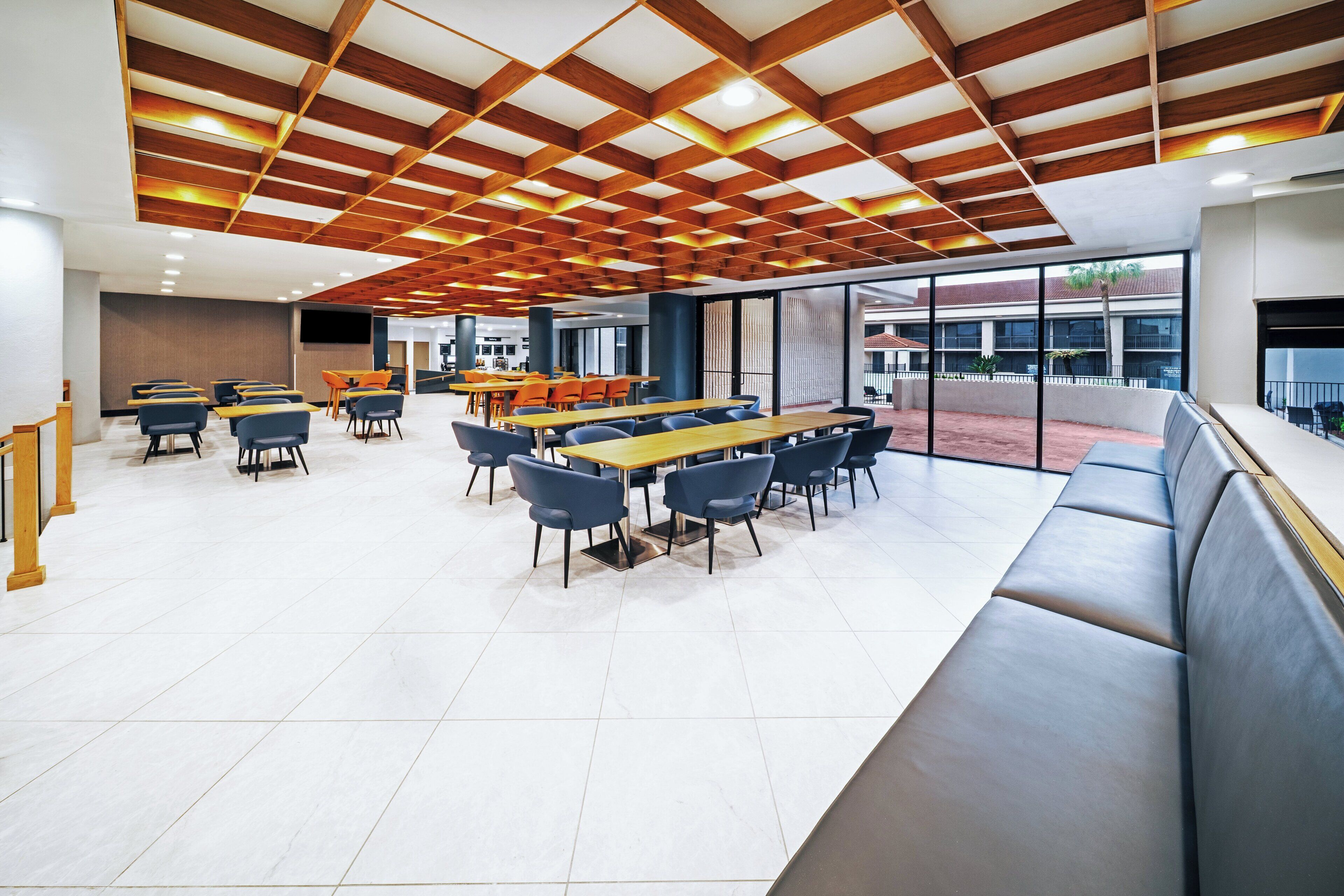 Un comedor moderno con mesas y sillas, un ventanal y vistas al exterior.