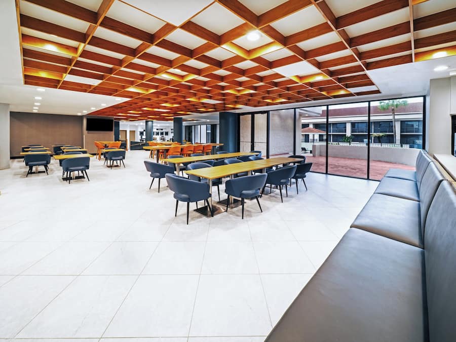 A modern dining area with tables and chairs, a large window, and a view of the outside.