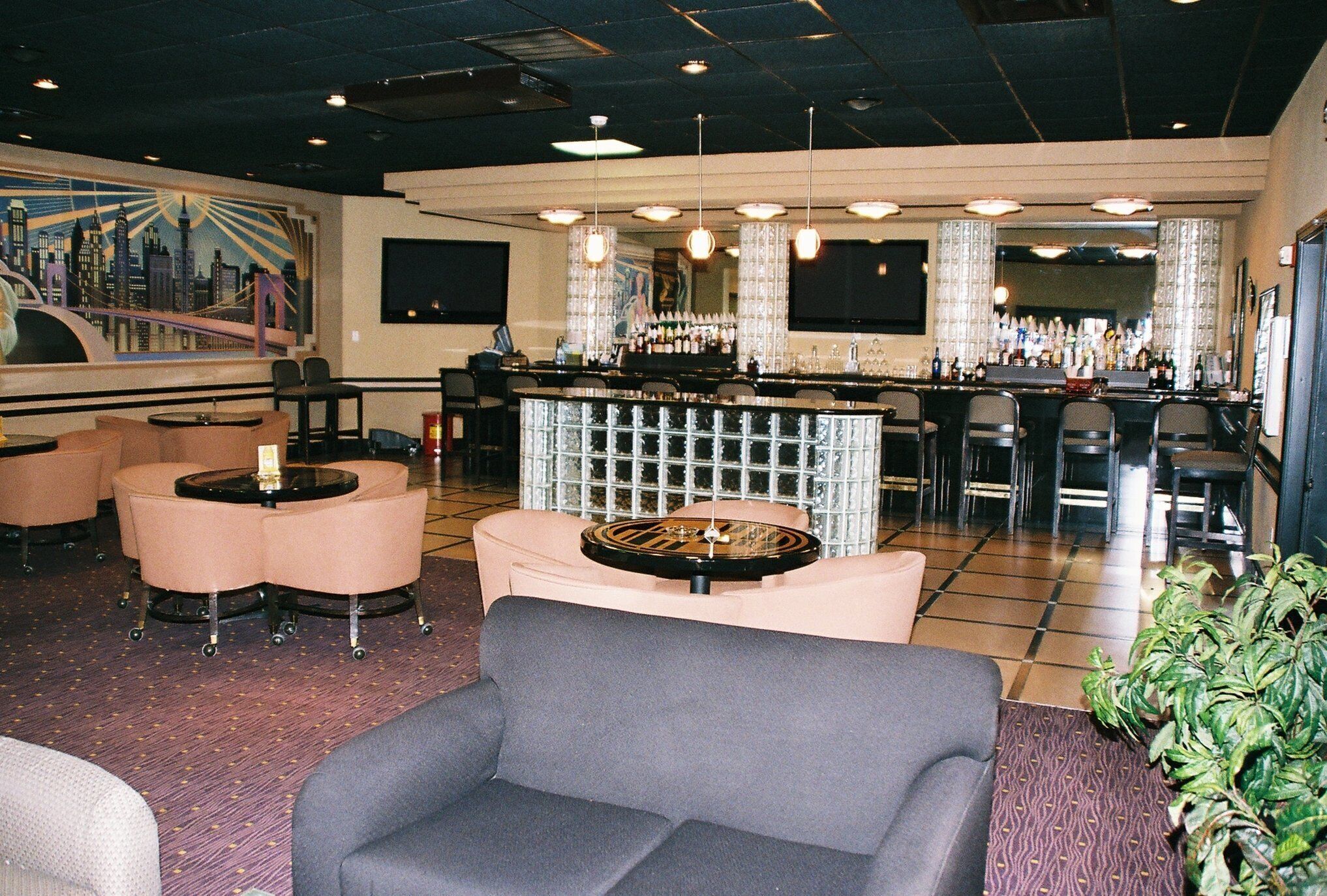A bar area with multiple seating options, including round tables and bar stools.