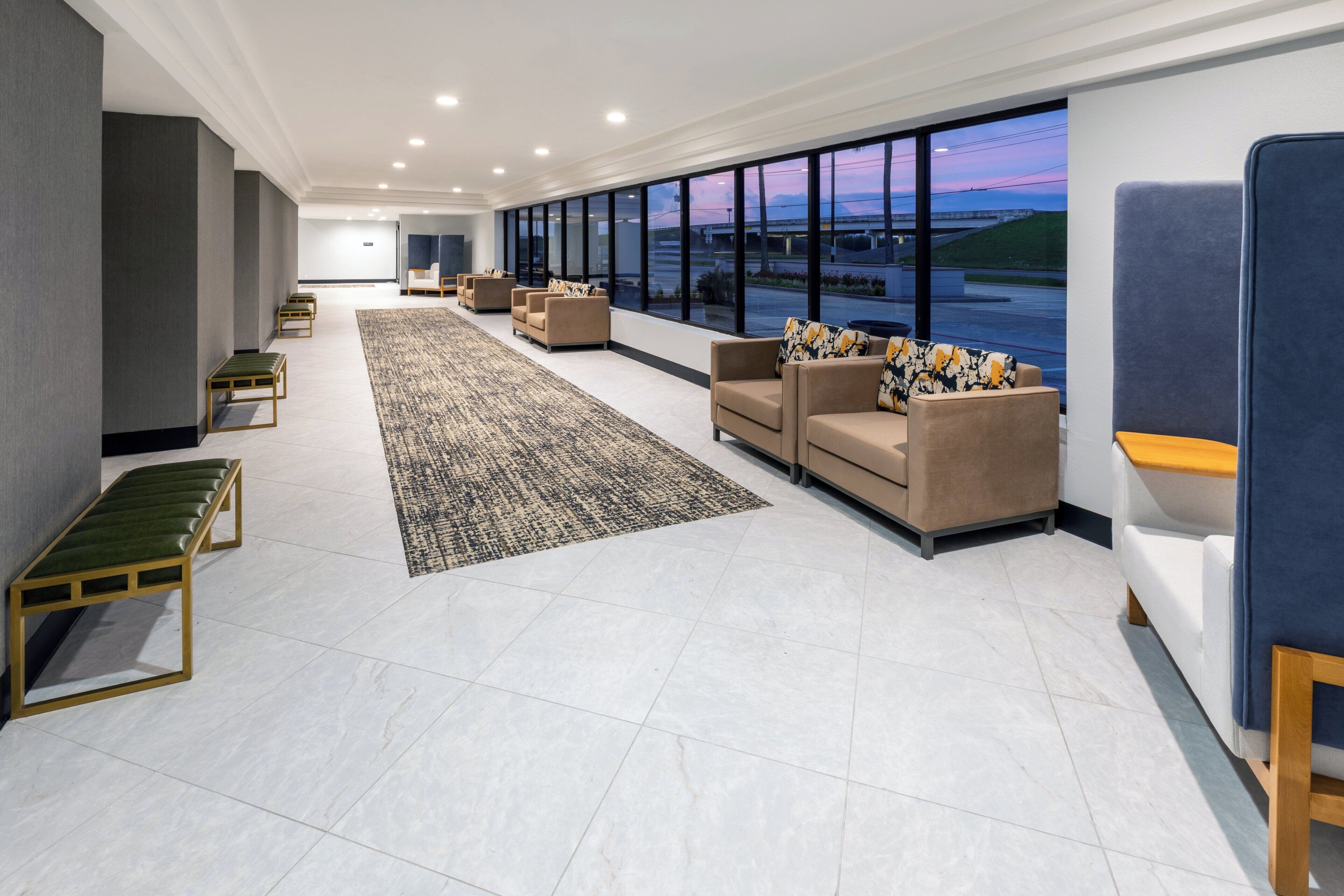 A modern lobby with seating, a patterned rug, and large windows offering a view.