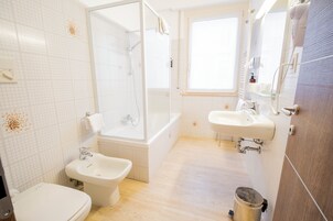 A modern bathroom with a bathtub, bidet, and separate sink.