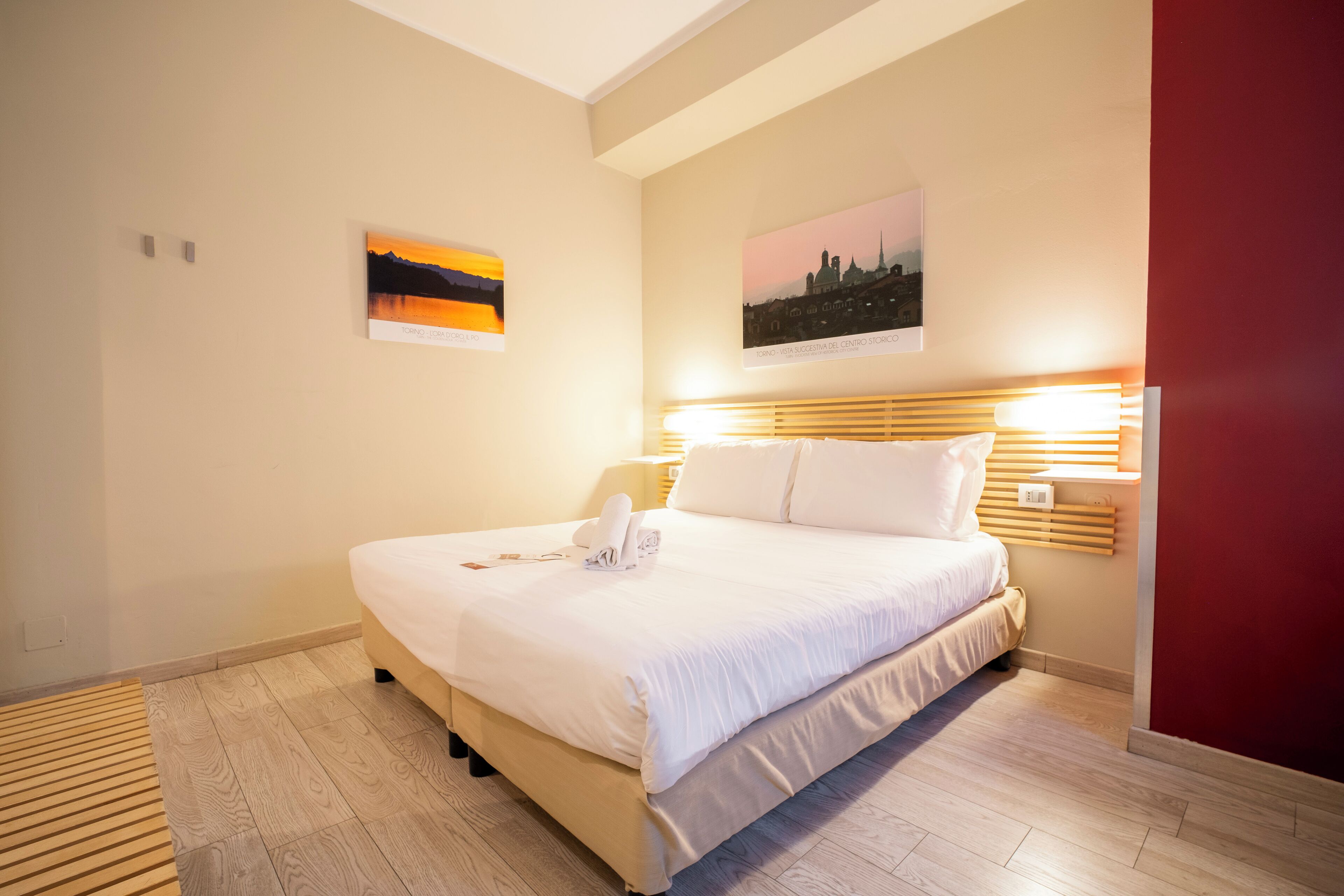 Una habitación de hotel con una cama grande, un cabecero de madera y dos lámparas fijadas a la pared.