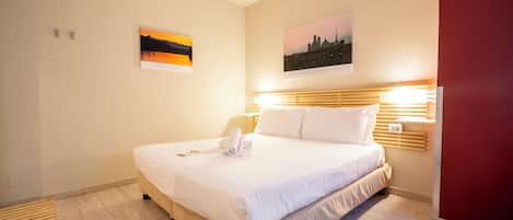 Una habitación de hotel con una cama grande, un cabecero de madera y dos lámparas fijadas a la pared.