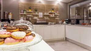 A kitchen area with a display of assorted donuts on a glass stand. - Best Quality Hotel Gran Mogol (Turin)