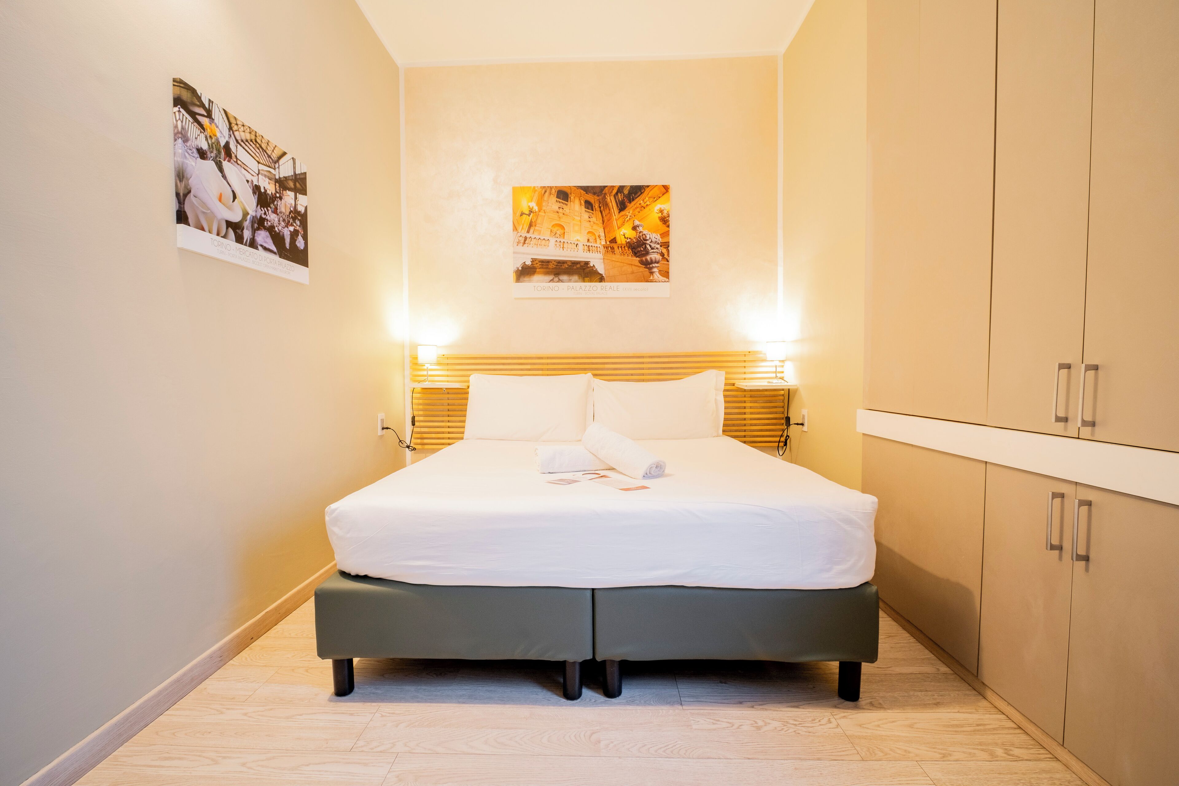 Una camera da letto ordinata con un letto, abat-jour e un armadio.