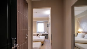 A hotel room with a wooden door, a bed with white bedding, a bedside table, and a small desk with a chair. - Best Quality Hotel Gran Mogol (Turin)