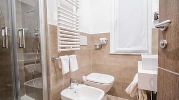 Un baño moderno con cabina de ducha de vidrio, un lavabo blanco, un inodoro y un perchero para toallas.