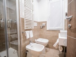 Un baño moderno con cabina de ducha de vidrio, un lavabo blanco, un inodoro y un perchero para toallas.