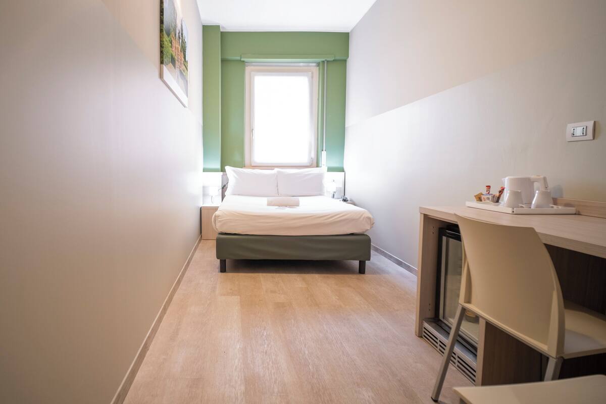 Une petite pièce comprenant un lit, un bureau et une chaise.