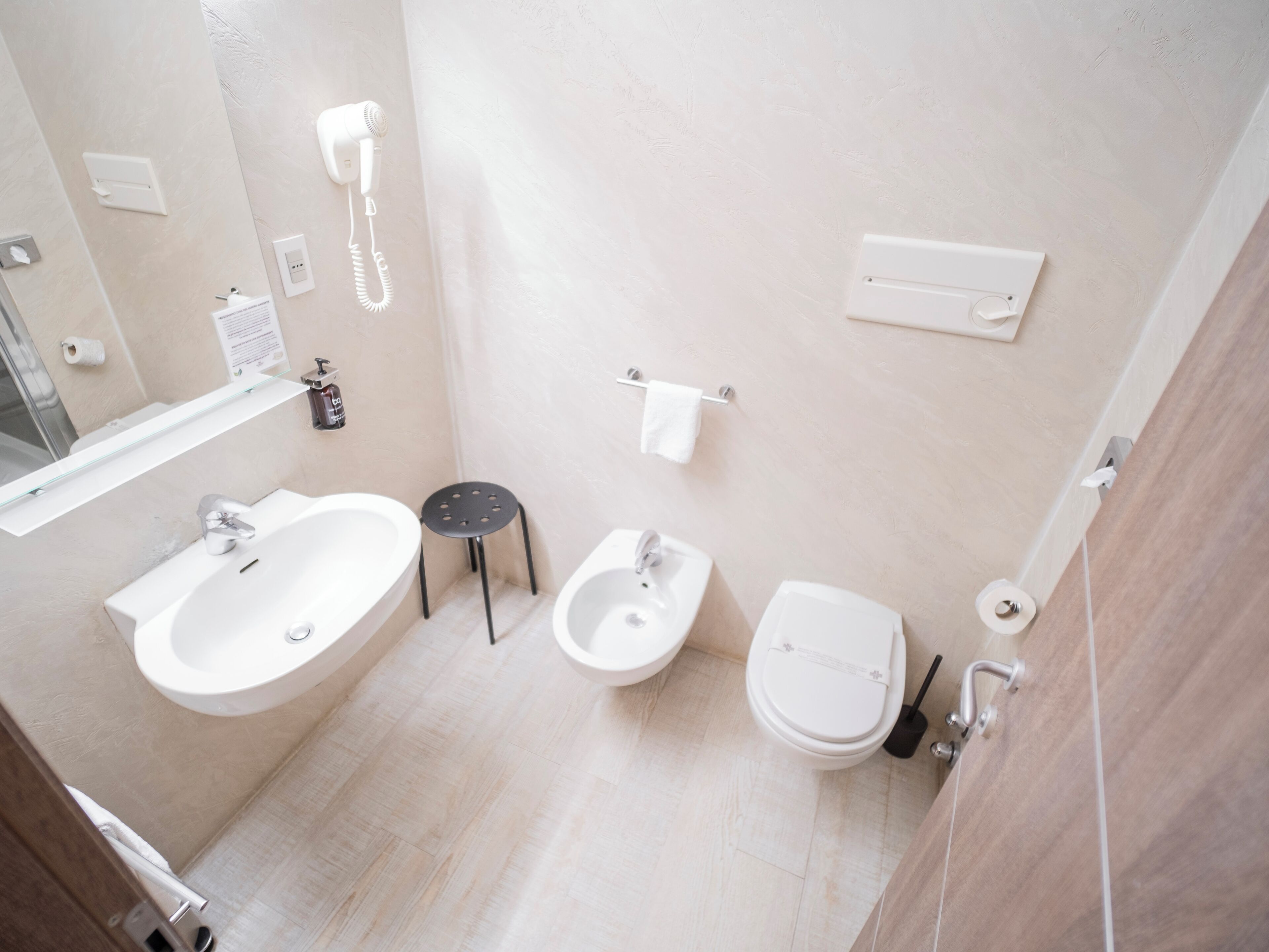 Un bagno moderno con un lavandino ampio, un bidet, un water e un asciugacapelli fissato alla parete.