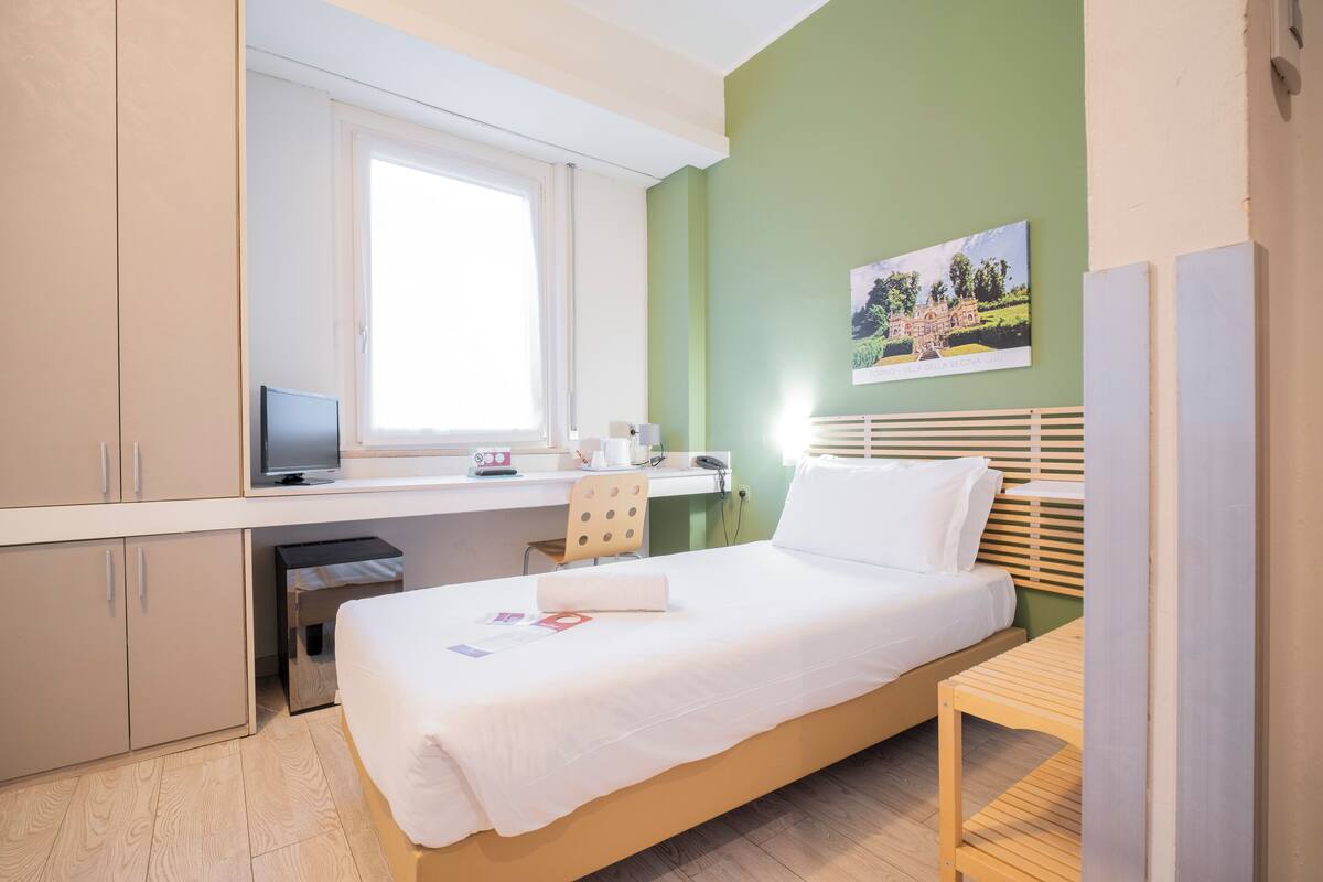 Une chambre à coucher avec un lit, un bureau, une chaise et une fenêtre.