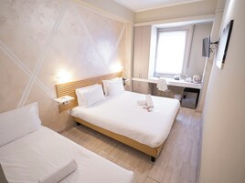 Una habitación de hotel con una cama grande, un escritorio y una ventana.