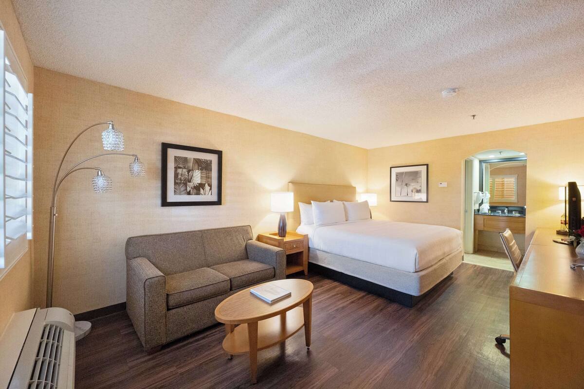 Ein Hotelzimmer mit Bett, Sofa, kleinem Tisch, Nachttisch und Lampe.