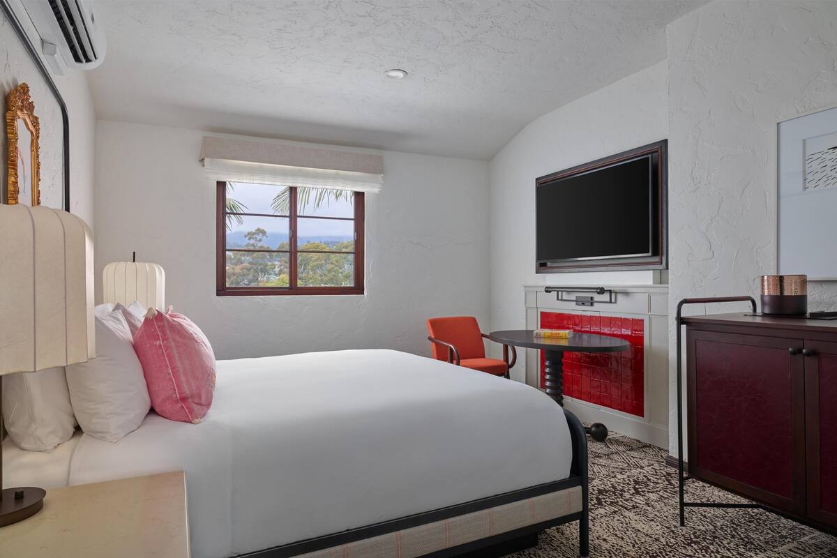 A hotel room with a bed, a TV, a small table, a chair, and a cabinet.