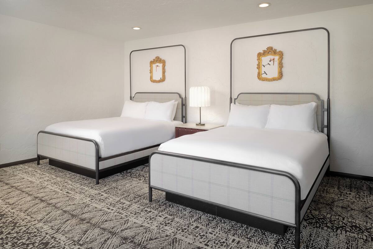 Two twin beds with metal frames, white bedding, and a patterned carpet.