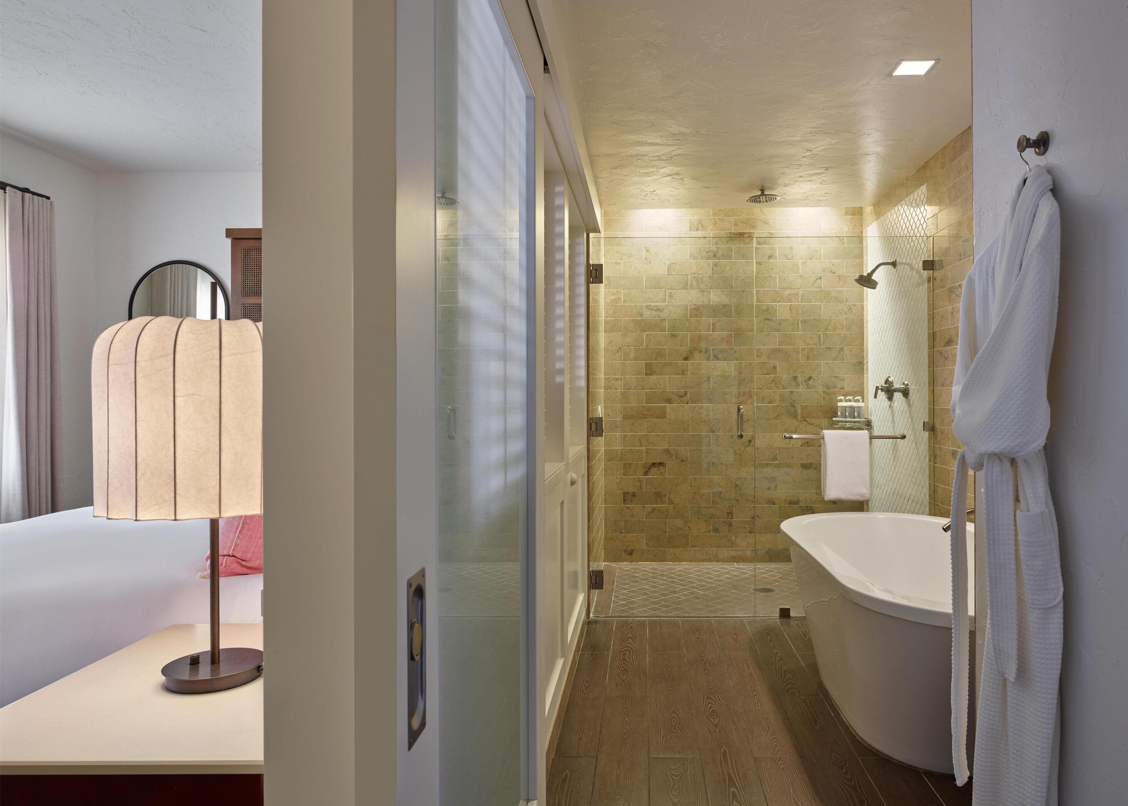 A hotel bathroom with a shower, a bathtub, a toilet, and a mirror.