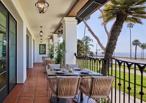 Ein AuĂenbereich zum Essen mit Tischen, StĂŒhlen und einer Umpachtungsanlage, mit Blick auf das Meer.
