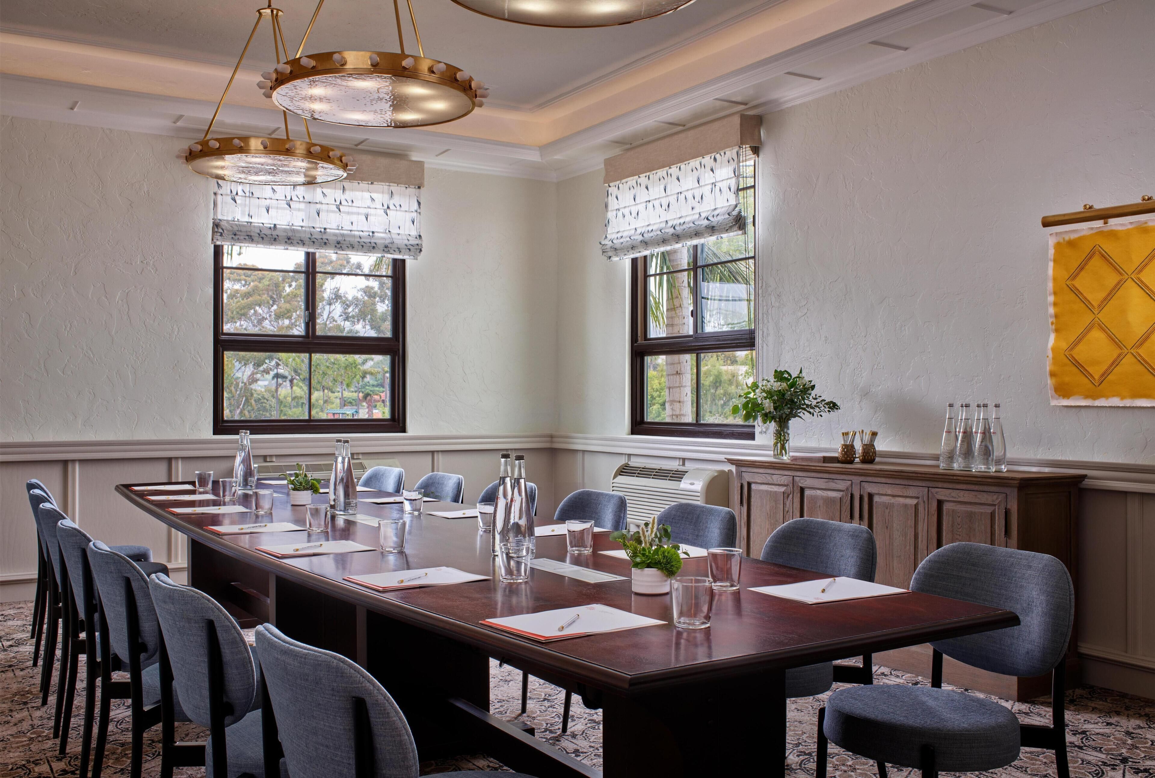A conference room with a long table, chairs, and a decorative plant.