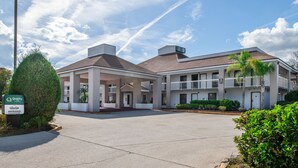 Un motel con entrada techada, varios balcones y cielo despejado.