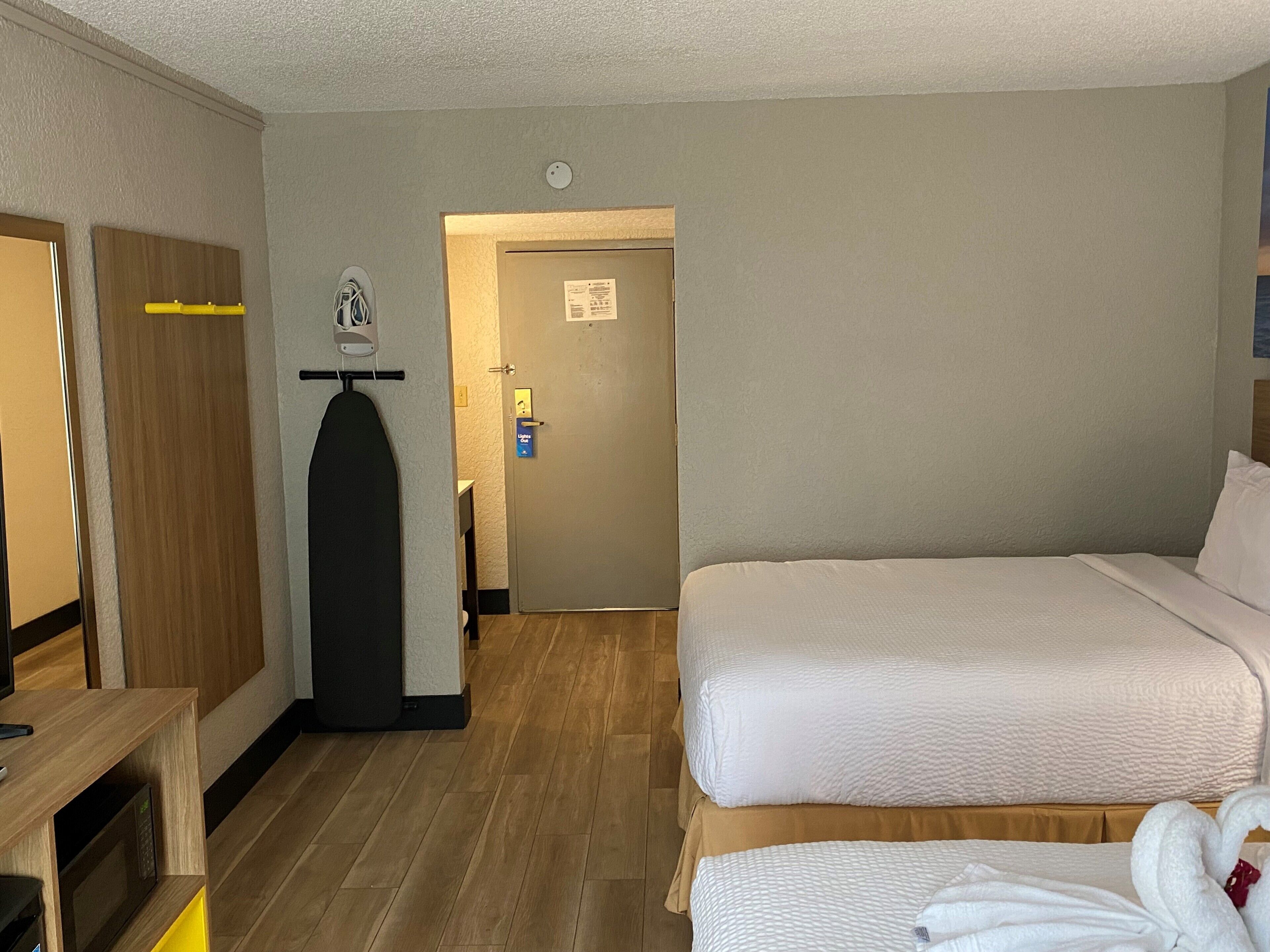 Een hotelkamer met een bed, een bureau, een magnetron, een kledingkast en een deur naar een badkamer.