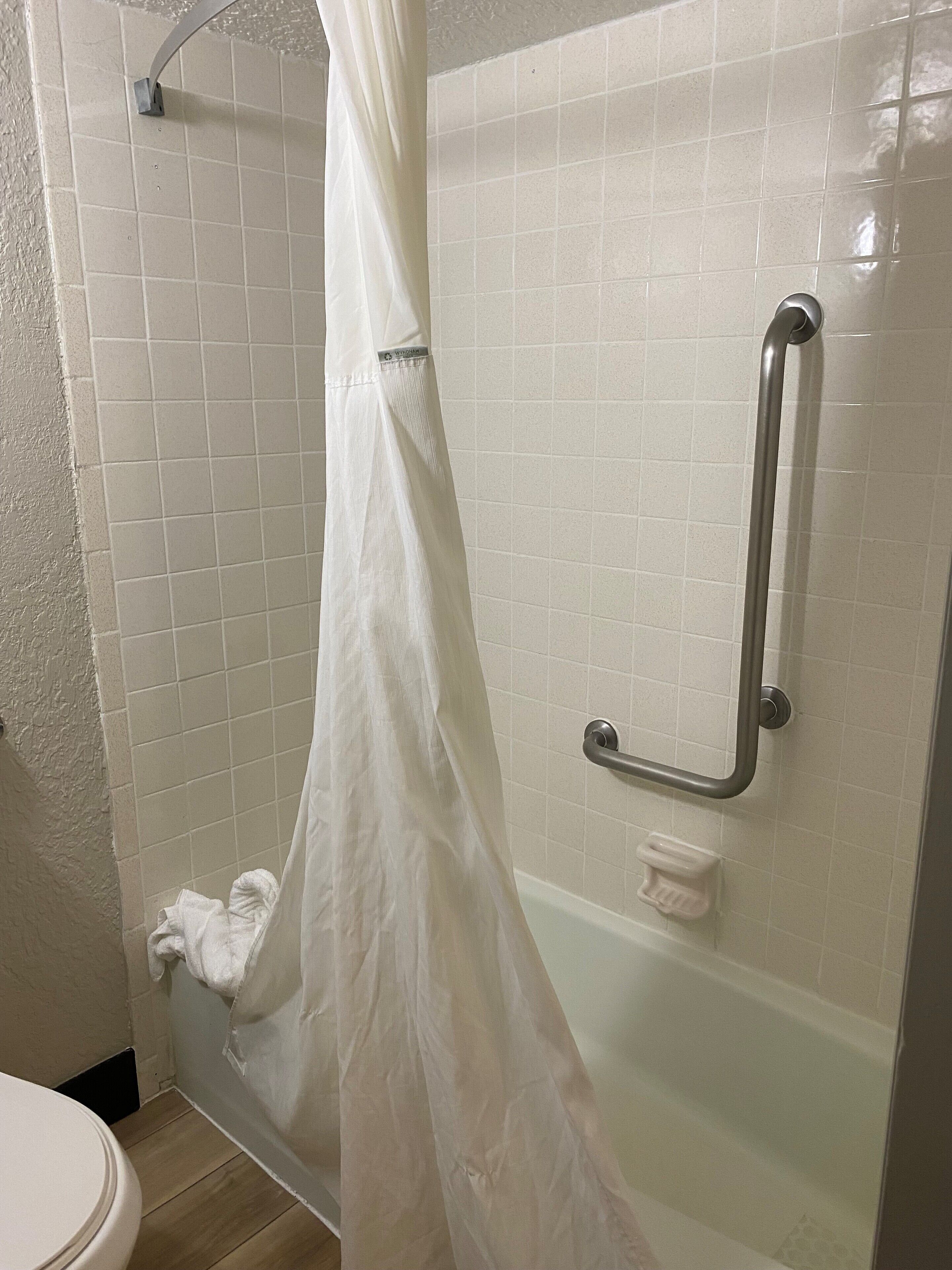 Een badkamer met een douche, een handgreep en een toilet.