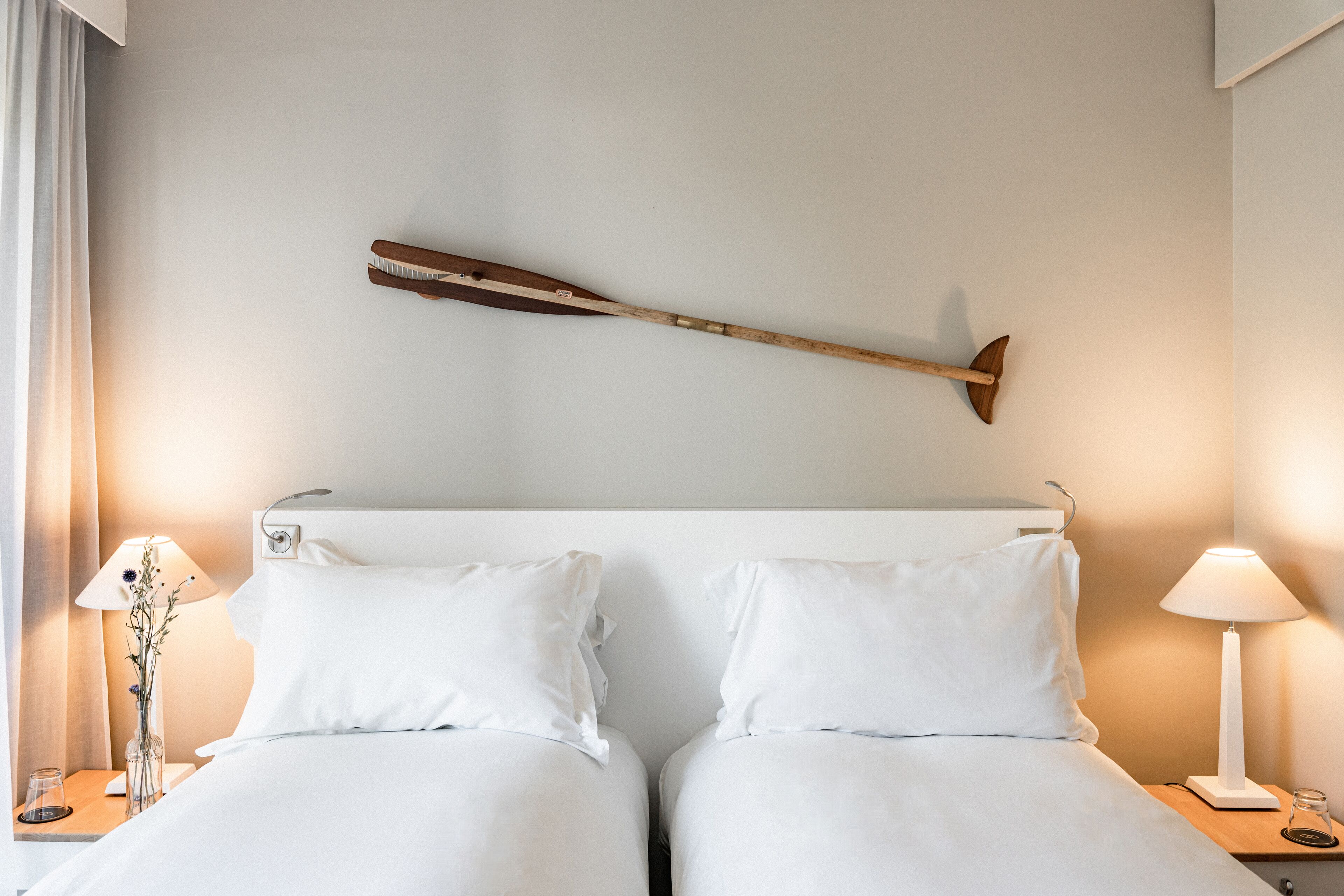 Une chambre d’hôtel avec deux lits, une décoration murale en bois, des lampes de chevet et un vase avec des fleurs.