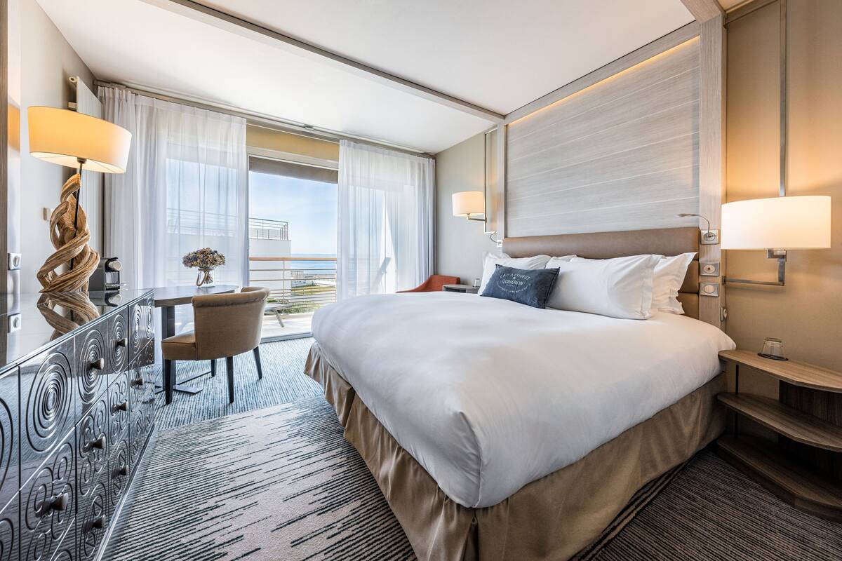 Ein Hotelzimmer mit einem großen Bett, einem Schreibtisch und Blick auf die Stadt.