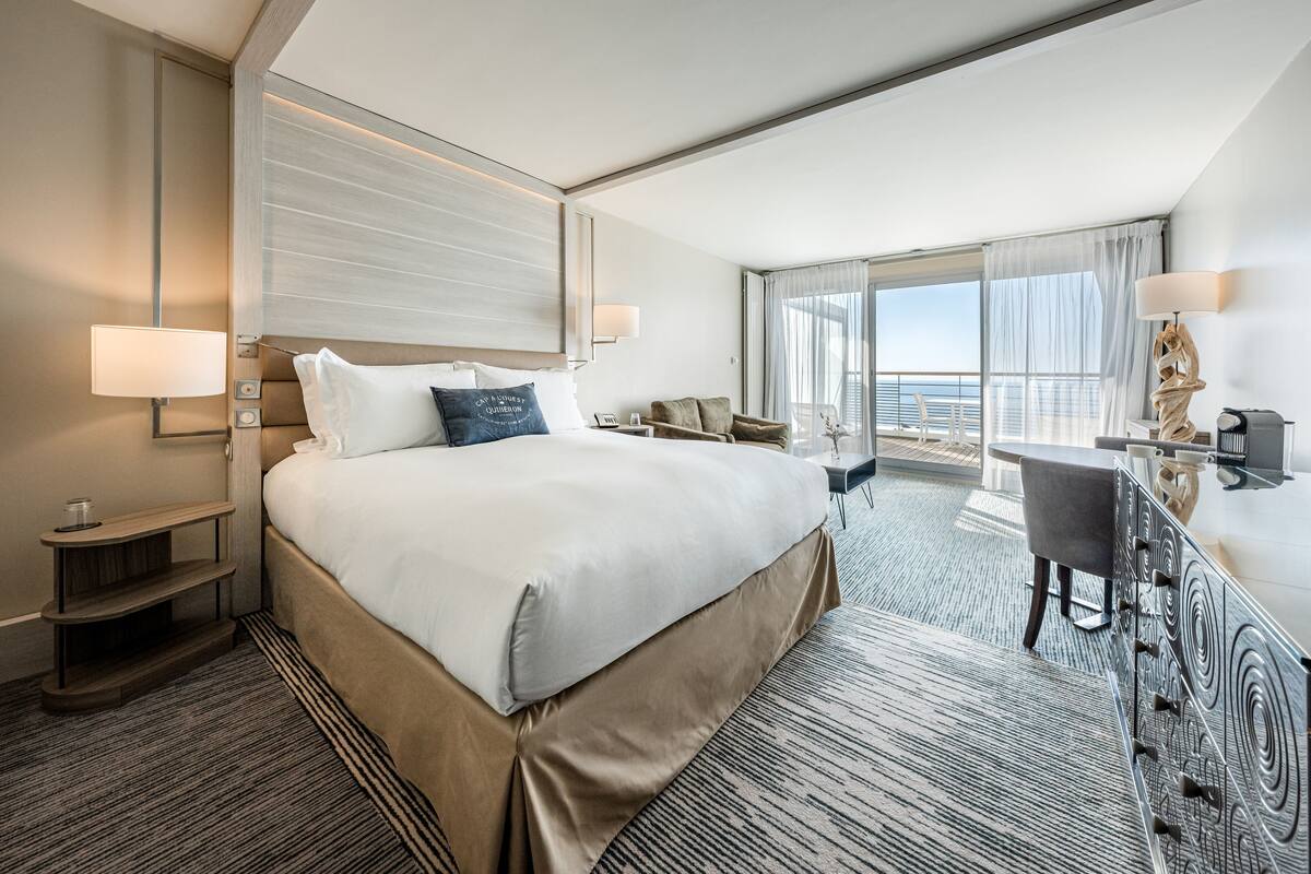 Ein modernes Hotelzimmer mit einem großen Bett, einem Schreibtisch und Blick auf den Ozean.
