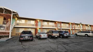 A motel with multiple floors, a parking lot with several cars, and a gated entrance.