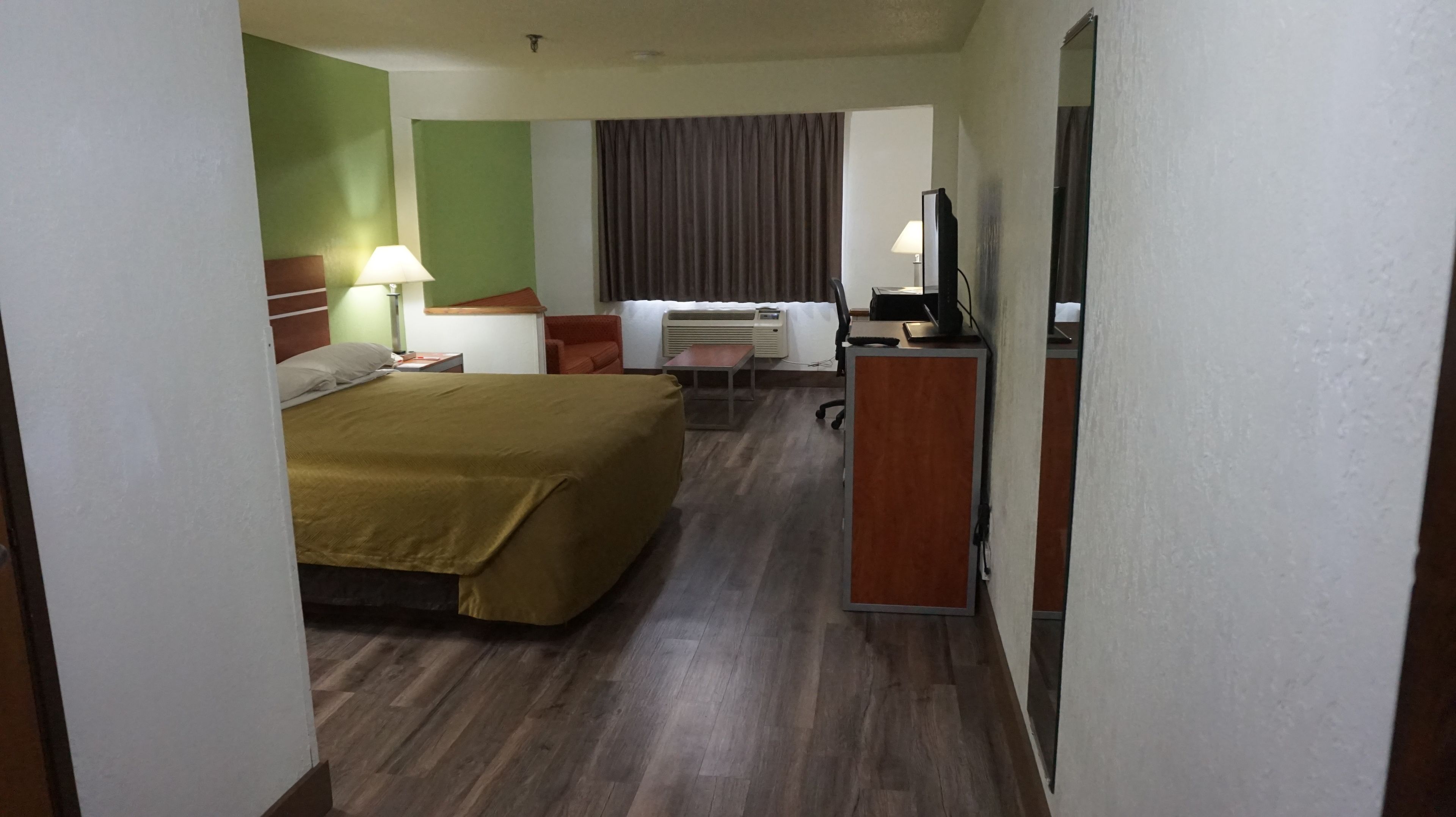 Ein Hotelzimmer mit einem Bett, einem Schreibtisch, einem Sessel, einer Lampe und einem Fernseher.