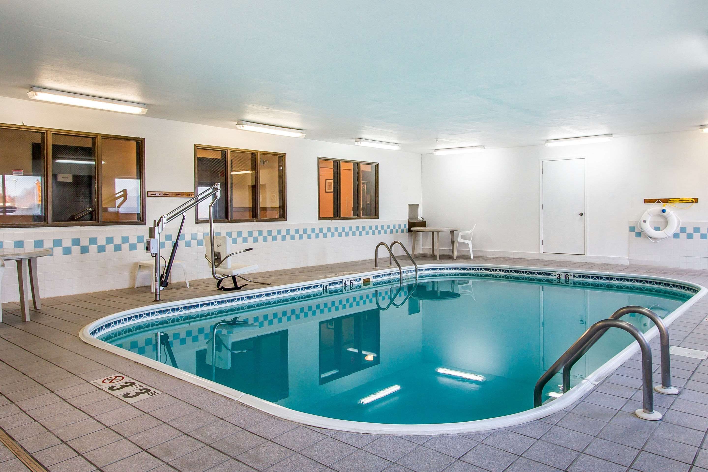 Una piscina interna con pavimento piastrellato, una scala per la piscina e un galleggiante appeso al muro.