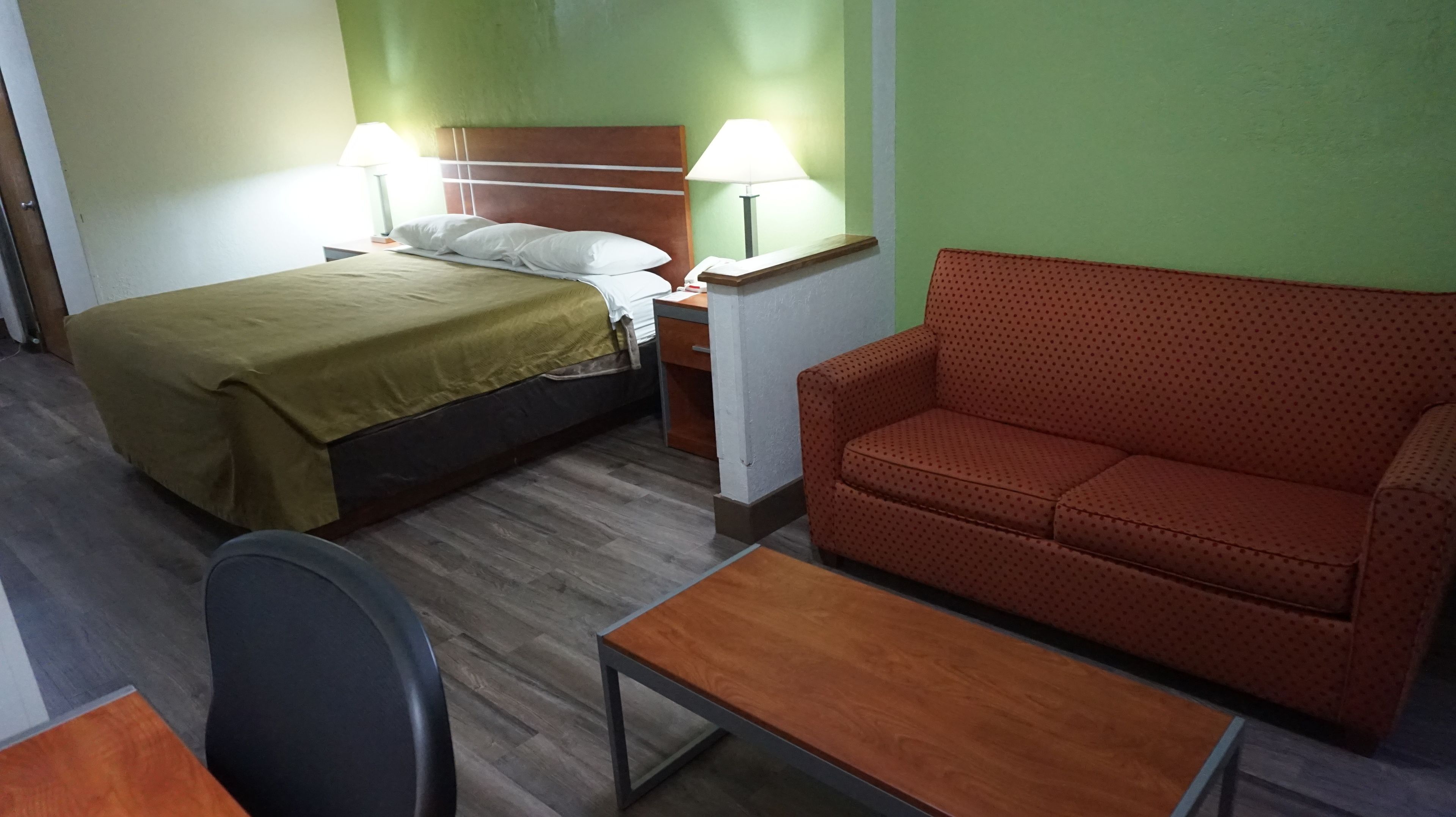 A hotel room with a bed, a sofa, a table, and two bedside lamps.