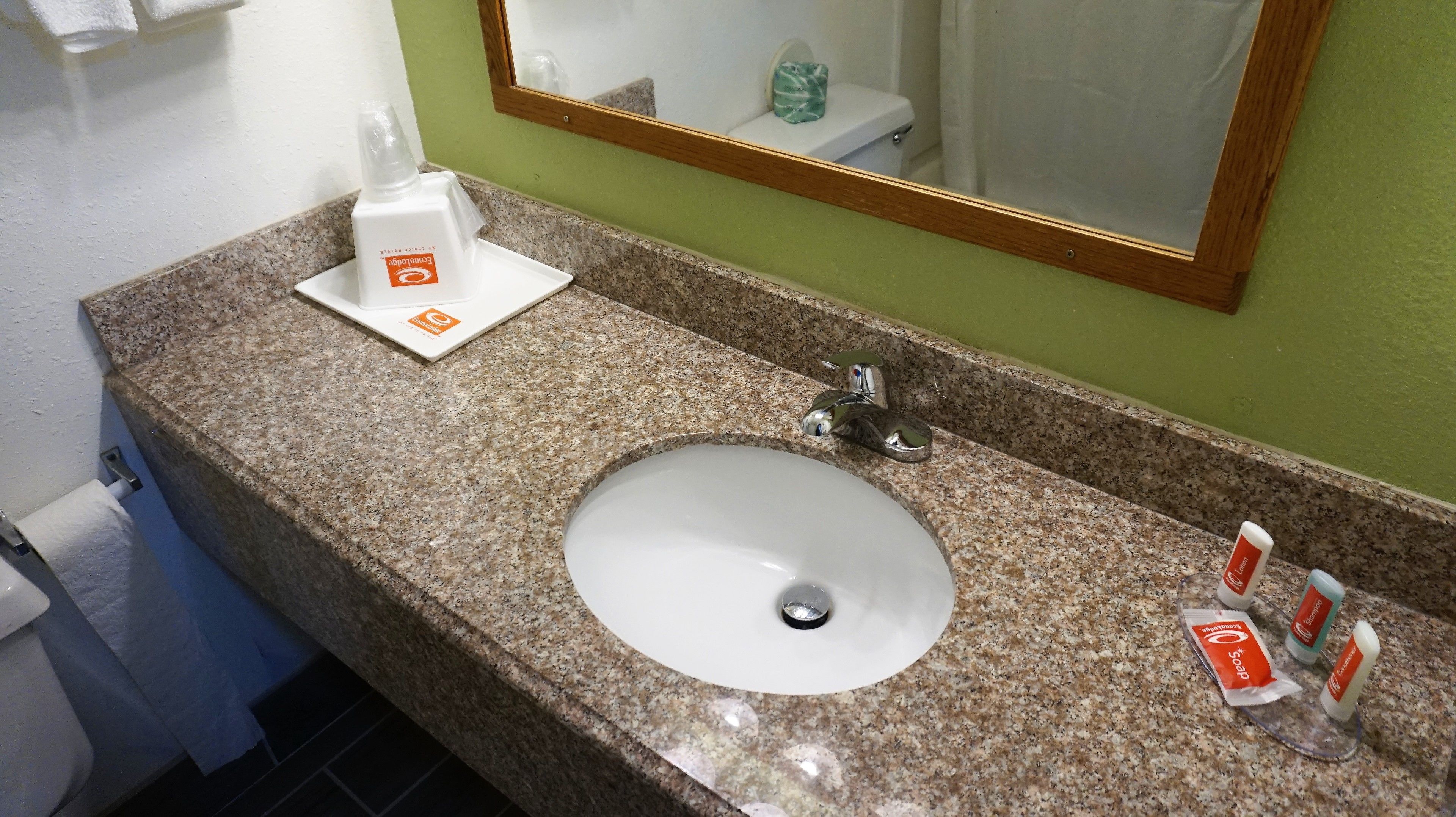 A bathroom with a granite countertop, a white sink, and a mirror. There are toiletries on the counter, including soap and a bottle of hand sanitizer.