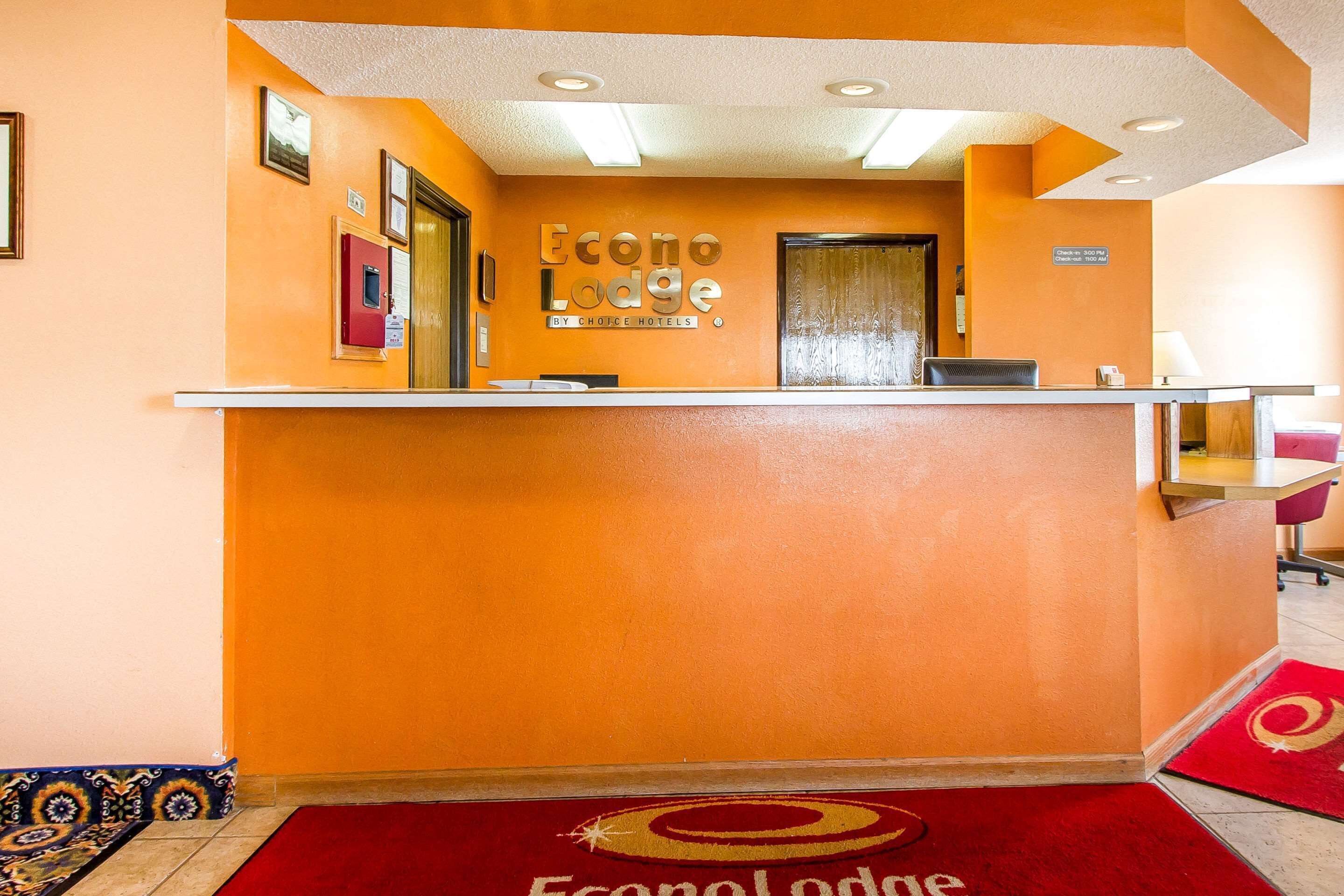 Un comptoir d’accueil à l’Econo Lodge, avec un tapis rouge et une enseigne au-dessus.
