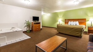 Quarto de hotel com uma cama grande, uma escrivaninha, banheiro com banheira e televisão.