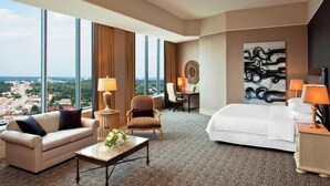 Una habitación de hotel con un ventanal grande, una cama, un sofá, un escritorio y una silla.