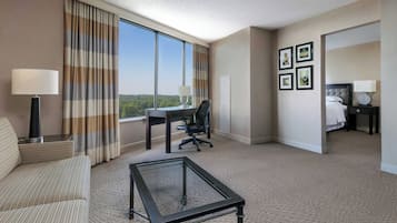 Una habitación de hotel con un ventanal grande, un escritorio, una silla, una cama y una mesita de café.