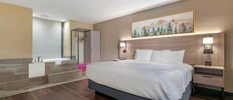 Ein Hotelzimmer mit einem großen Bett, einem Badezimmer mit Badewanne und einem Gemälde an der Wand.